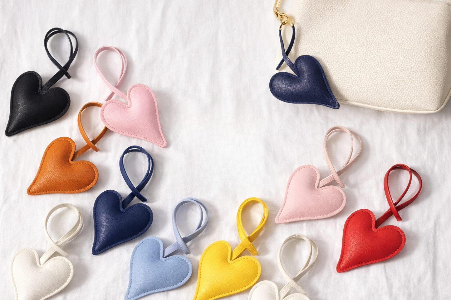 Various colors of Carry Your Heart Collection Leather Heart Bag Charm on white background.