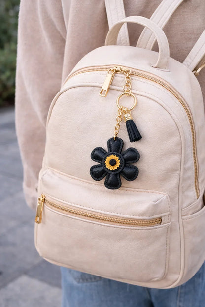 Black leather flower bag charm styled on a white back pack.