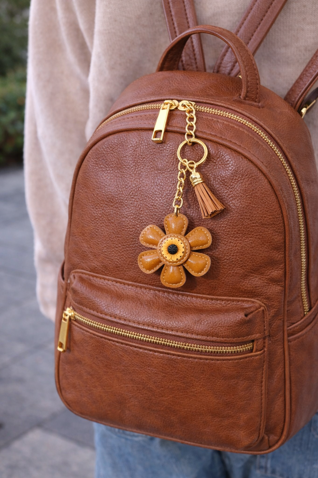 Brown leather flower bag charm styled on a Brown back pack.