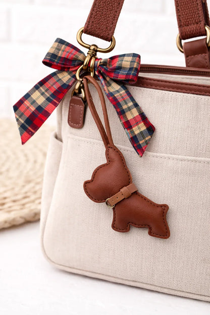 Ruby colored  Pocket Puppy Leather Bag Charm  with collar on a white purse with scarf. 