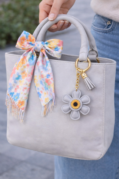 Grey leather flower bag charm styled on a summer tote bag.