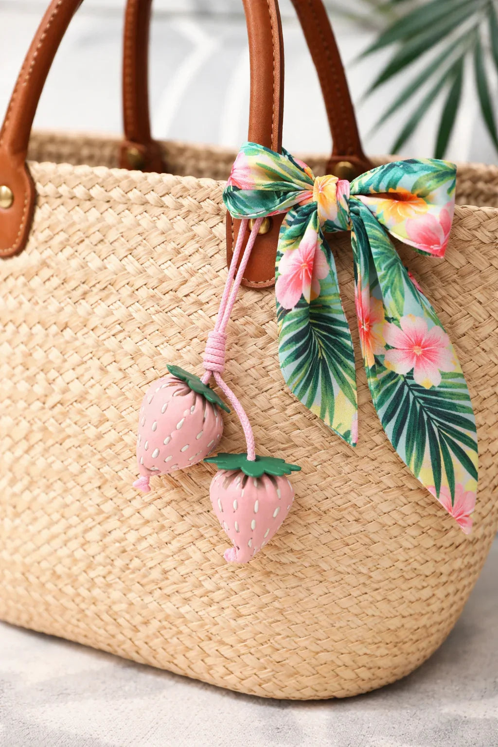 Pink Fraise Duet Strawberry Bag Charm Set with leather cord strap on straw bag with scarf. 