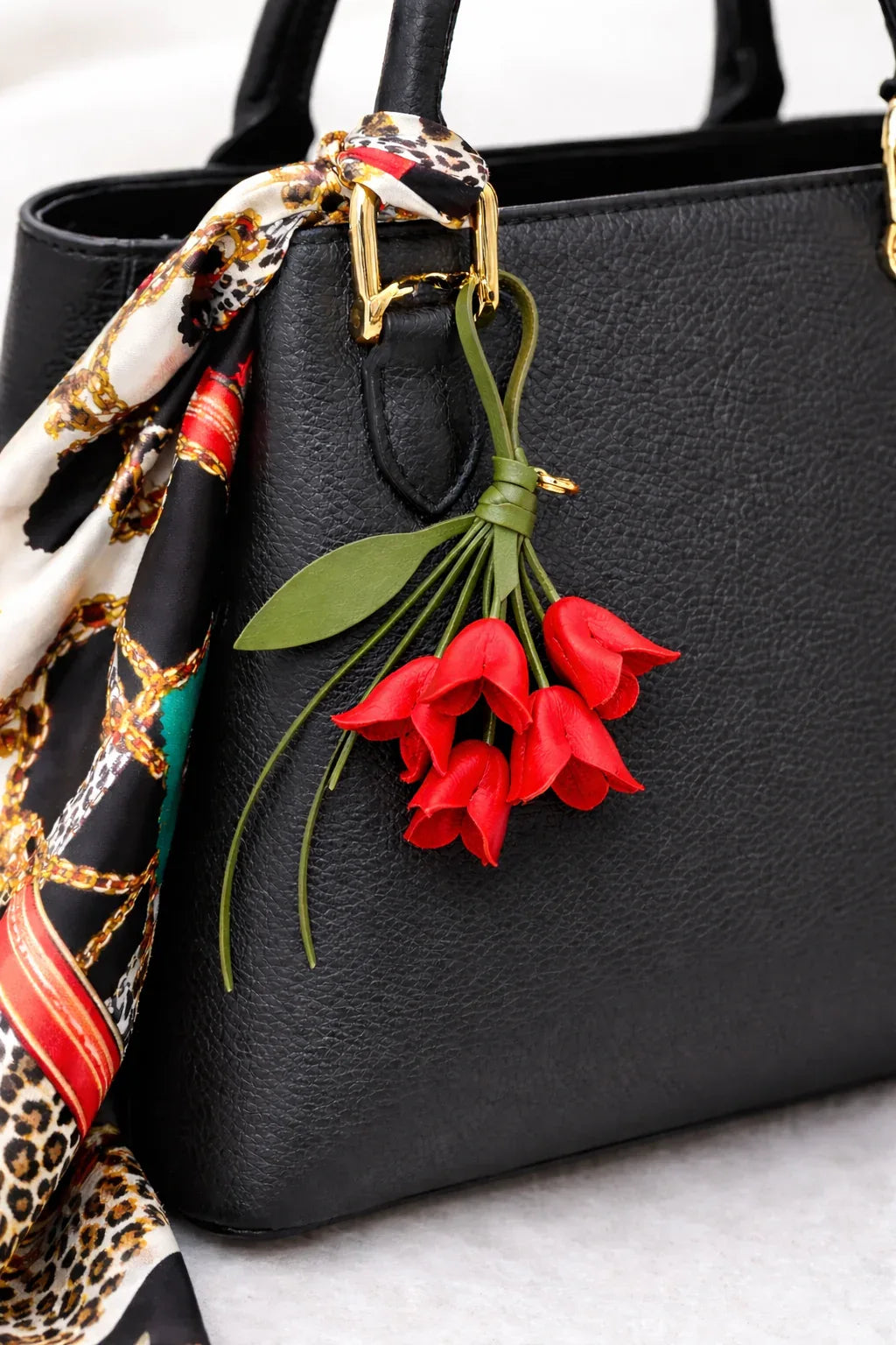 Red Petite Lily Bag Charm  with leather strap on black purse with scarf. 