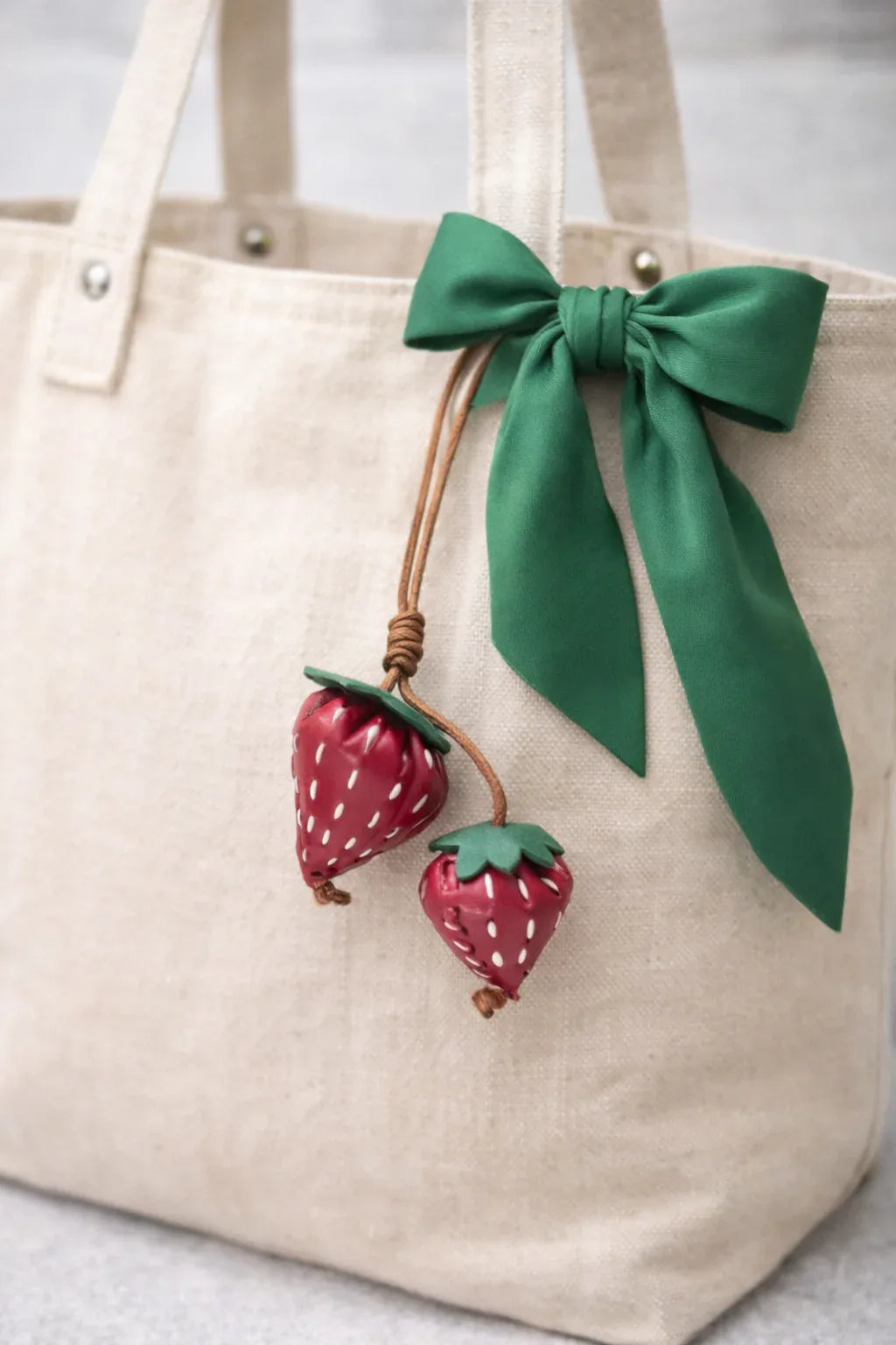 Red Fraise Duet Strawberry Bag Charm Set with leather cord strap o white tote bag and green scarf. 