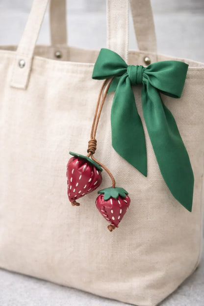 Red Fraise Duet Strawberry Bag Charm Set with leather cord strap o white tote bag and green scarf. 