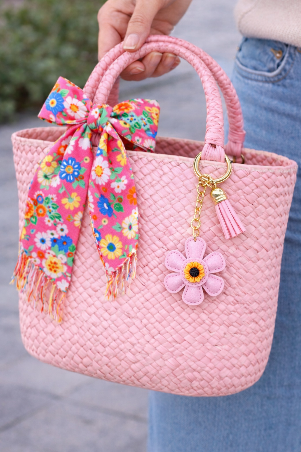 White  leather flower bag charm styled on a straw summer tote bag.