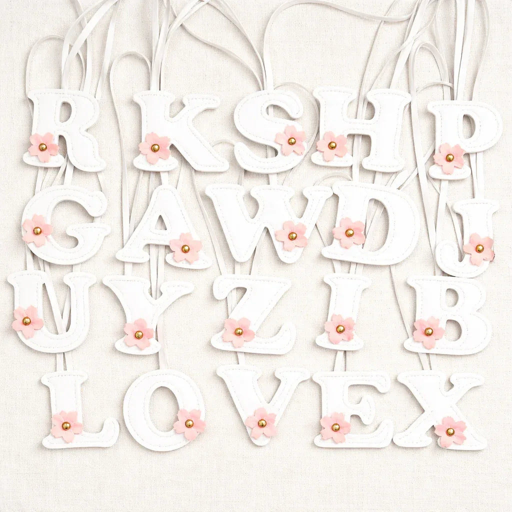 Various Initials in Bloom Alphabet Bag Charms  with leather strap on white background. 