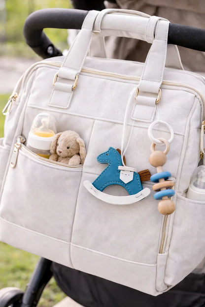 Blue Rockabye Keepsake Horse Charm on white diaper bag on stroller. 