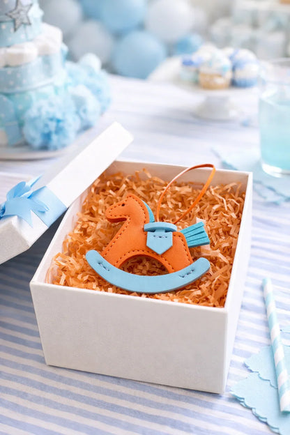 Orange Rockabye Keepsake Horse Charm in decorative gift box with birthday background. 