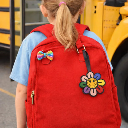 Child walking to bus with a multi colored  Smiles in Bloom Daisy Bag Charm on an orange backpack. 
