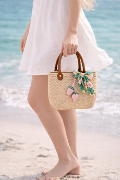 Woman walking on beach holding stew bag with Pink Fraise Duet Strawberry Bag Charm.