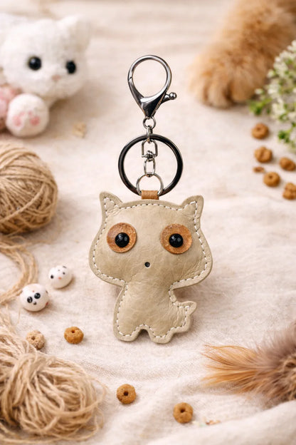 Tan handmade leather cat keychain with a minimalist silhouette and silver metal key ring.