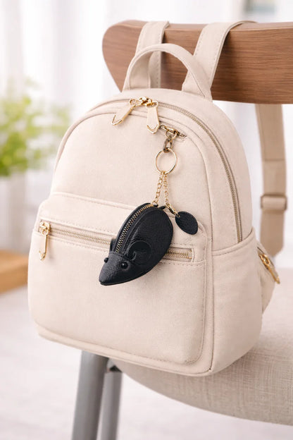 Handcrafted black  leather mouse-shaped coin purse with round ears and a secure zipper and key chain, hanging on a bag to show size.