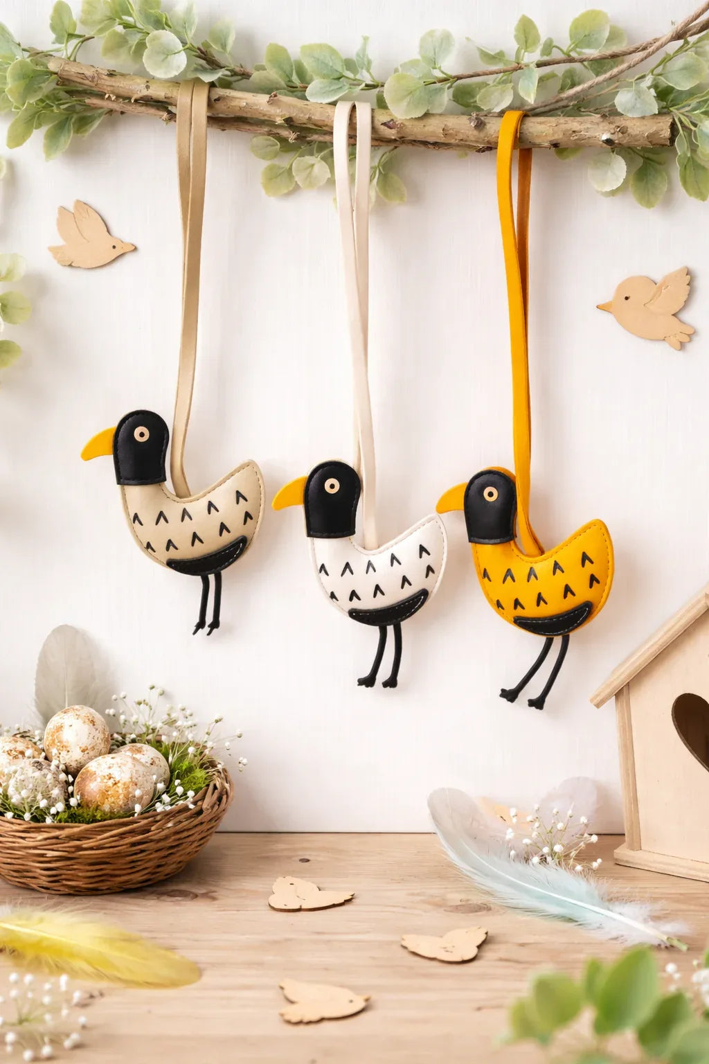 3 different colored Feathered Friend Leather Bag Charms  hanging on a branch.