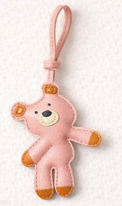Pink teddy bear leather bag charm with brown accents on a white background