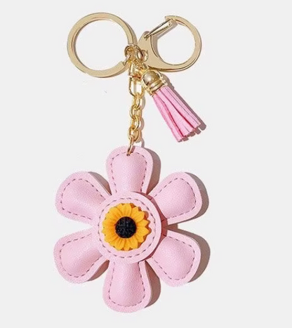 Handmade pink leather daisy keychain with yellow center and gold clasp.