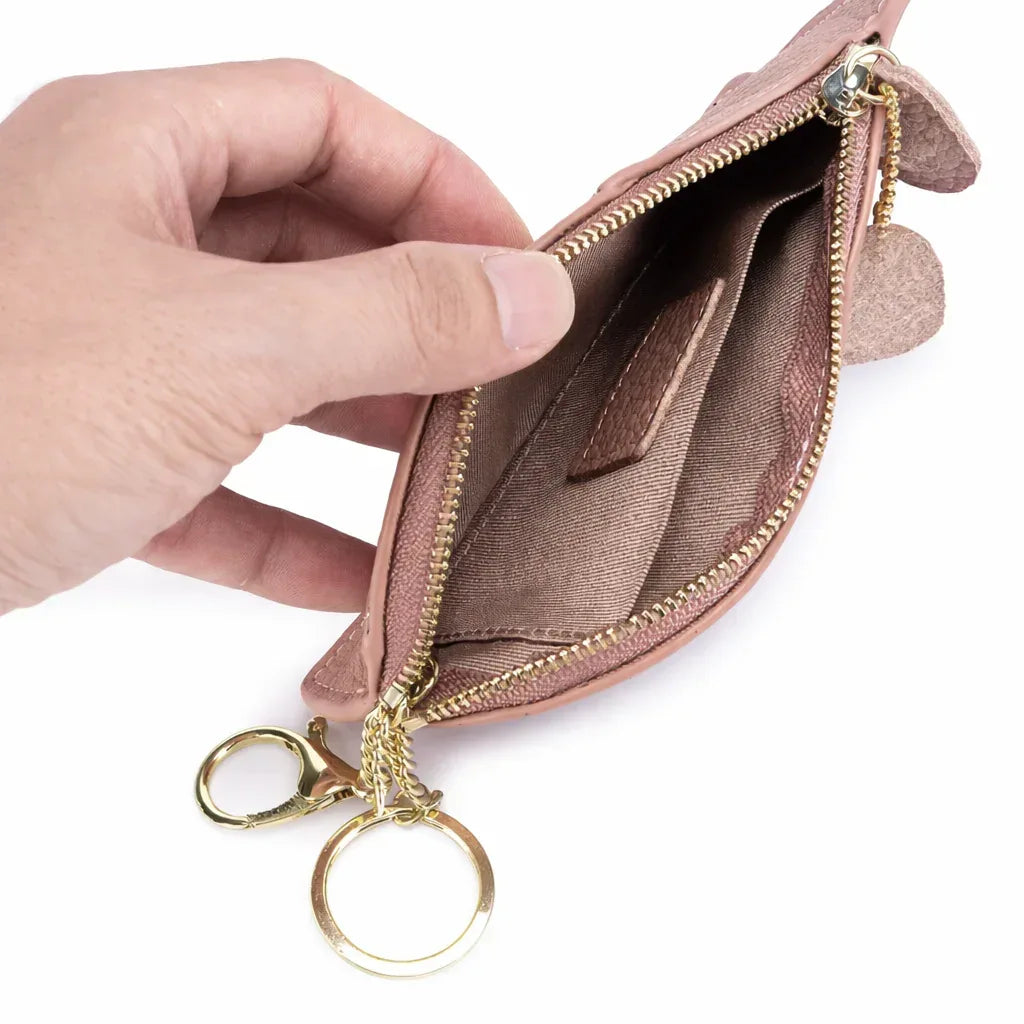 Mini cat-shaped leather coin wallet held in hand to show compact size for pocket or bag and quality of lining.