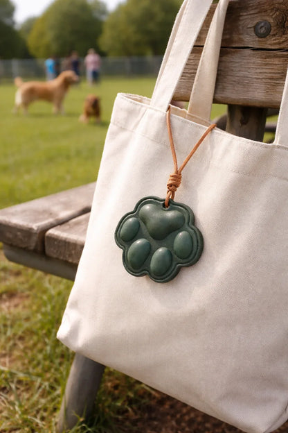 Everyday Companion Green Dog Paw Bag Charm  with leather strap on a white tote bag outside. 