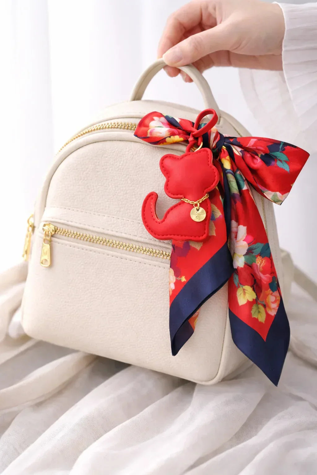 Red Cozy Kitty Handmade Leather Kitten Bag Charm with leather strap on a white purse with scarf . 