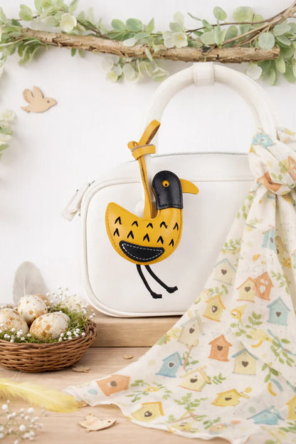 Golden Yellow Feathered Friend Leather Bag Charm  on white purse.
