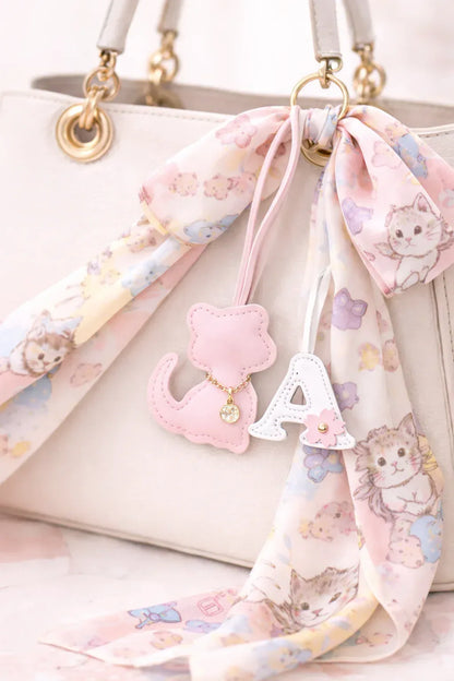 Light Pink  Cozy Kitty Handmade Leather Kitten Bag Charm with leather strap on a white purse with scarf and letter "A" bag charm. 