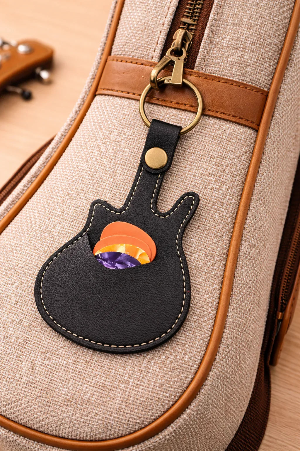 Black Pick Pocket guitar keychain clipped to a musician's tan  gig bag with zipper pull.