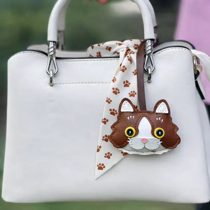 Brown Whiskered Heirloom Leather Cat Charm on white purse with scarf.
