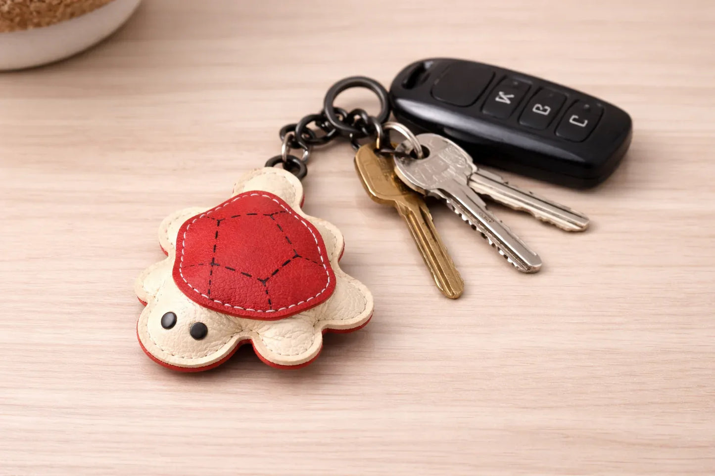 Red turtle leather key chain with keys attached to show size.