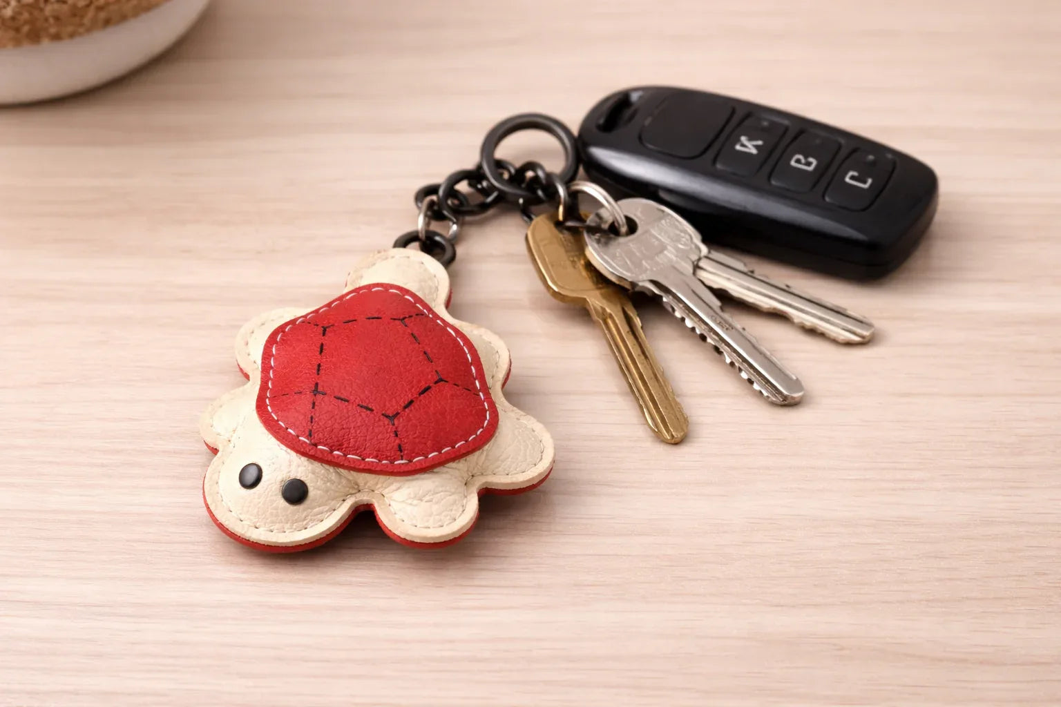 Red turtle leather key chain with keys attached to show size.
