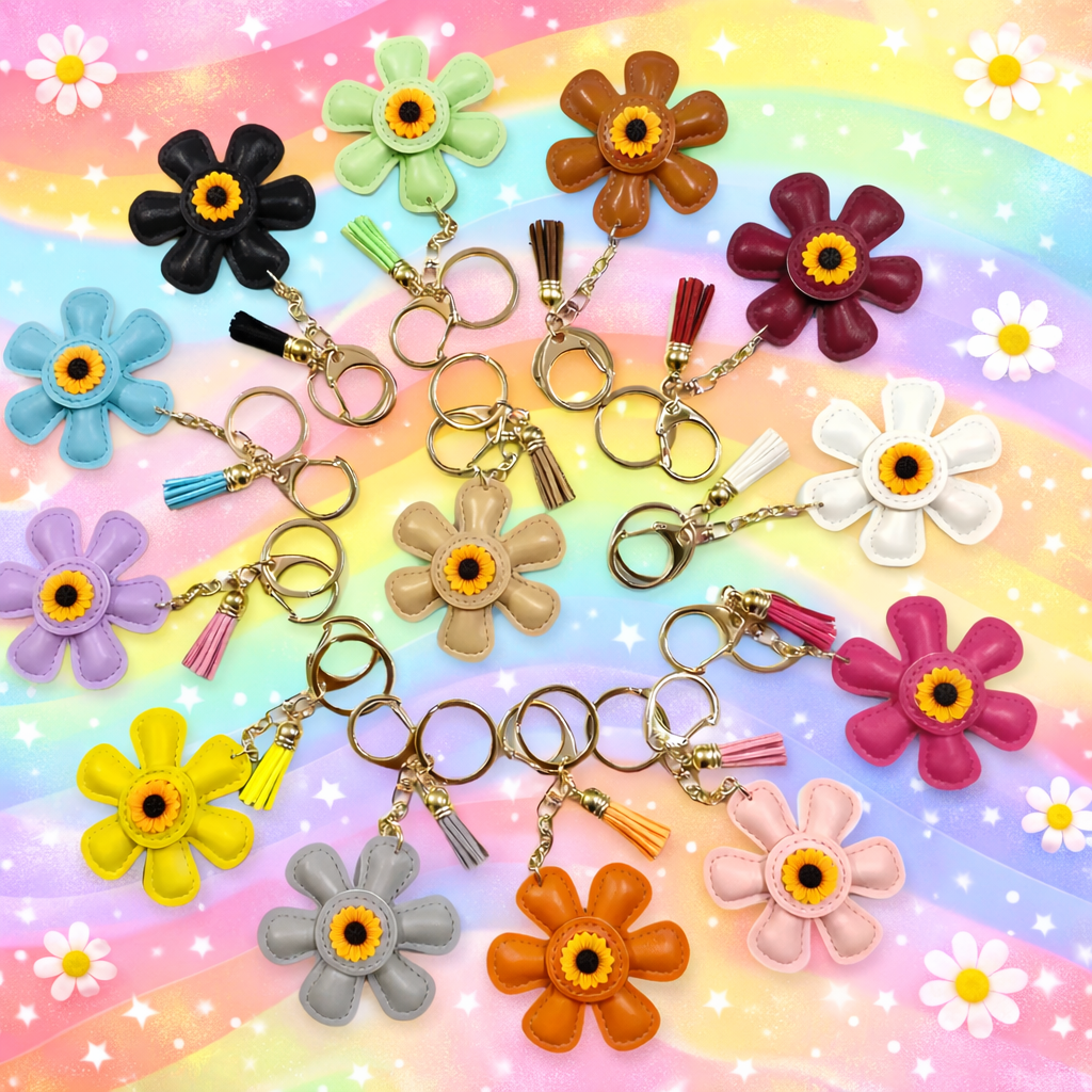 Assorted colorful leather flower keychains in daisy shapes from the Petal Parade collection on a rainbow colored table. 