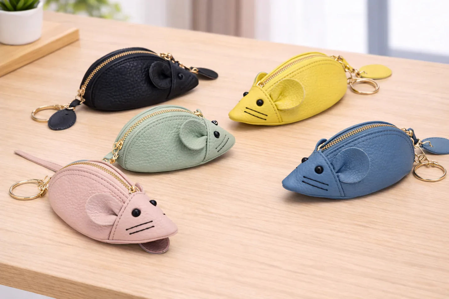5 Handcrafted  leather mouse-shaped coin purses with round ears and a secure zipper with key ring sitting on table. 