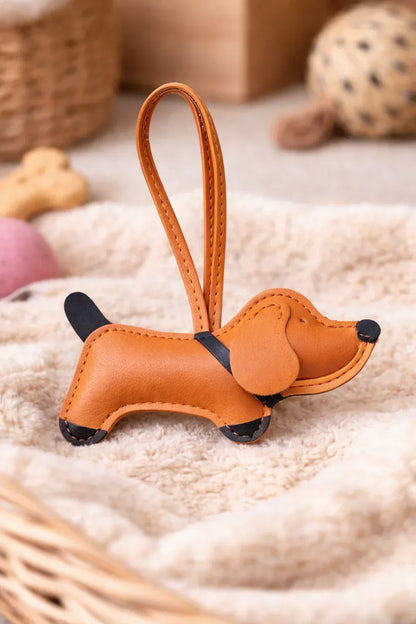 Chic Tan Leather Dachshund Bag Charm  with leather strap sitting on blanket. 