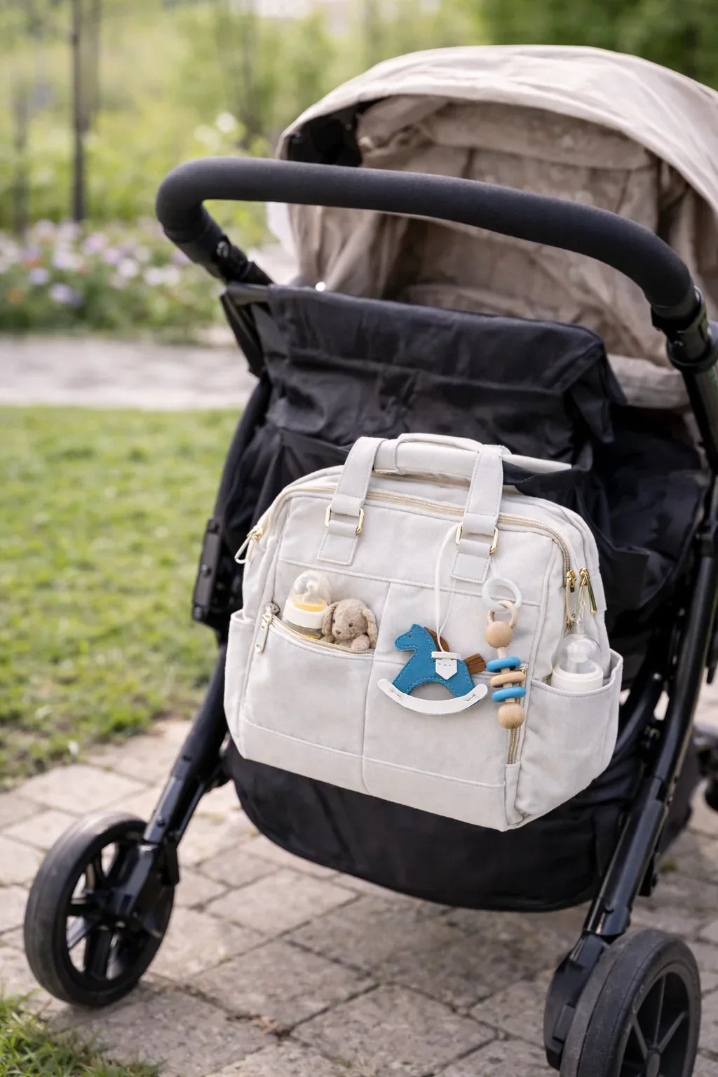 Purple Rockabye Keepsake Horse Charm on white diaper bag on stroller outside. 
