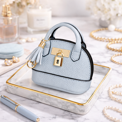 Petite light blue Leather Purse Lock & Key Bag Charm  with key ring and zipper on marble surface with pen and pearls. 
