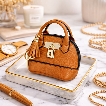 Petite orangeLeather Purse Lock & Key Bag Charm  with key ring and zipper on marble surface with pen and pearls. 