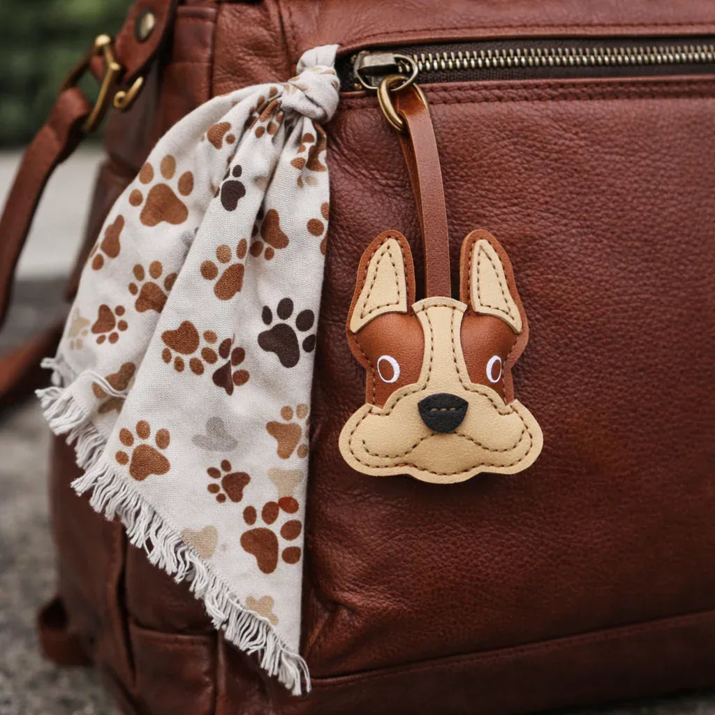 Tan Bulldog Leather Bag Charm with leather strap on brown backpack zipper.