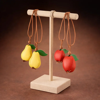 Pear and Apple Orchard Luxe Leather Fruit Bag Charms with leather strap hanging on display stand. 