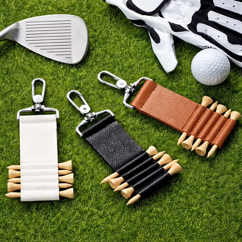 3 colors of  Leather Golf Tee Holder Keychain on grass and with golf accessories showing Tees in the holder. 