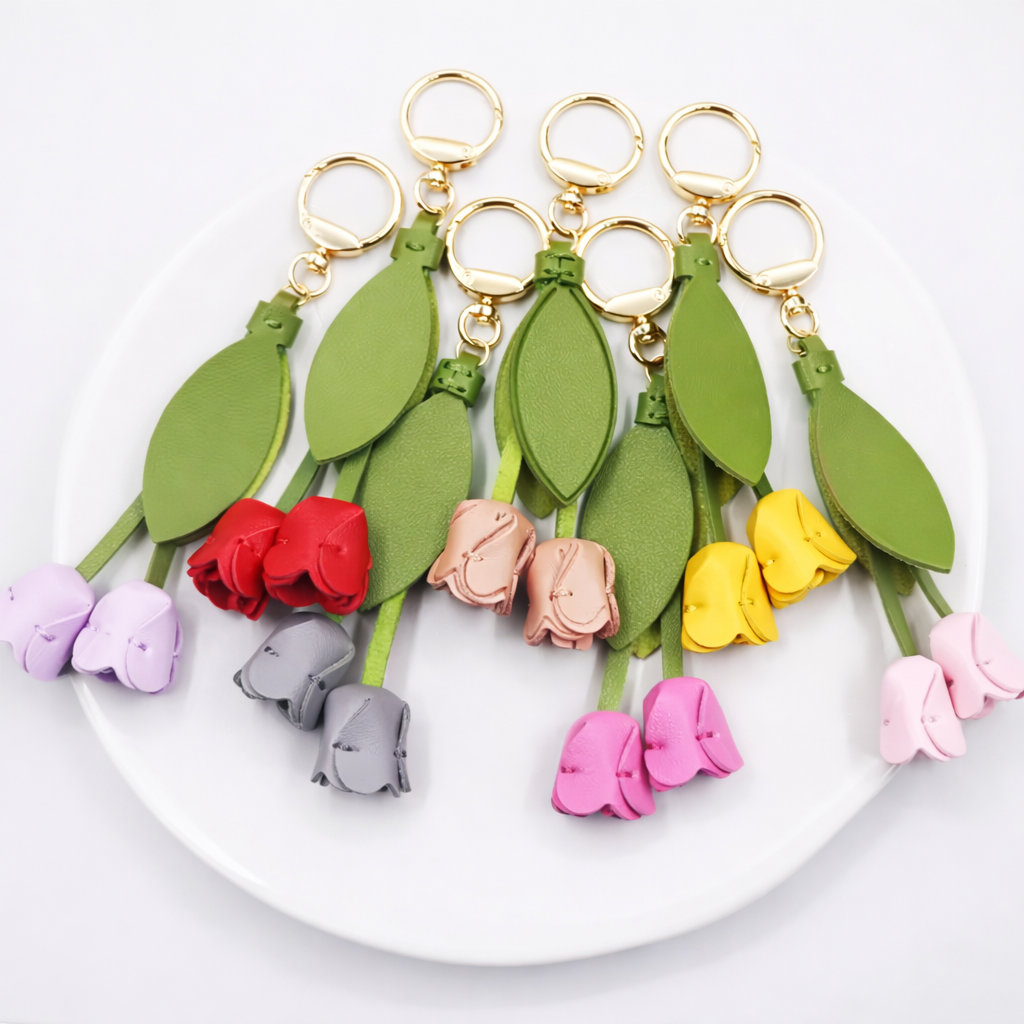 Various colored Sweetheart Tulip Bag Charms with key ring on white plate. 
