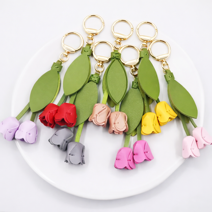 Various colored Sweetheart Tulip Bag Charms with key ring on white plate. 