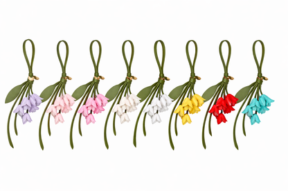 Set of colorful petite lily leather bag charms on green stems with ribbons against a white background