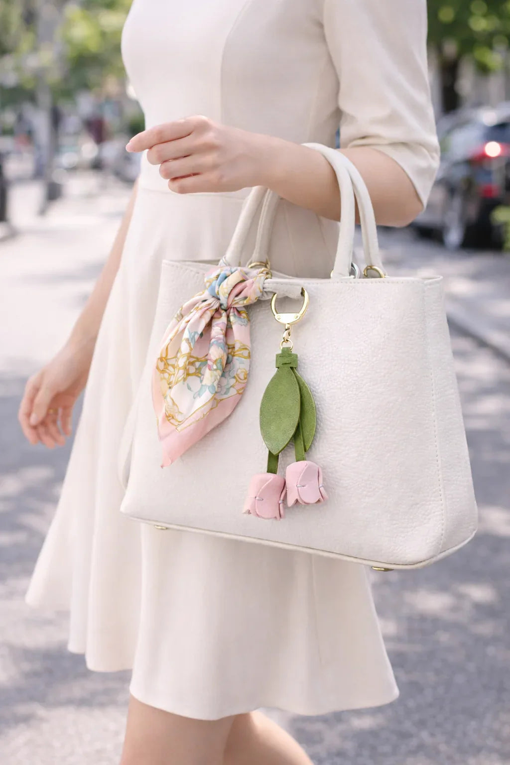 Woman walking holding a white purse with a white Sweetheart Tulip Bag Charm with key ring. 