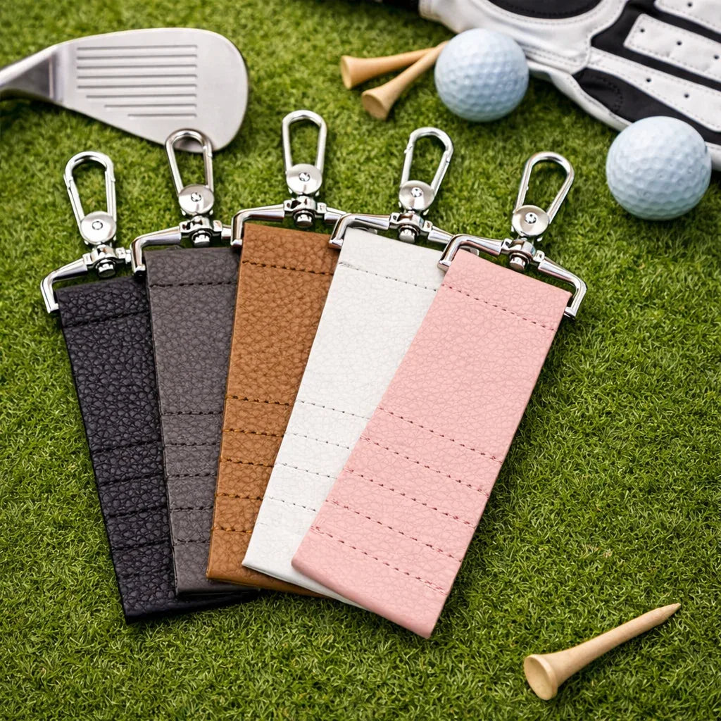 5 colors of Leather Golf Tee Holder Keychain on grass and with golf accessories.
