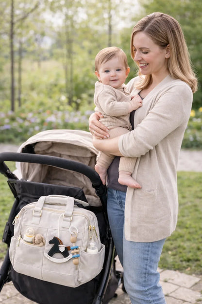 Woman holding baby with Black Rockabye Keepsake Horse Charm on white diaper bag on stroller. 