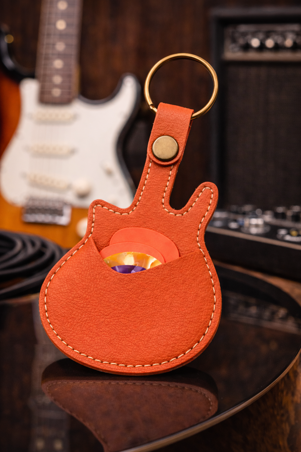 Handmade orange guitar-shaped leather keychain with a secure pick pocket and brass-tone ring.