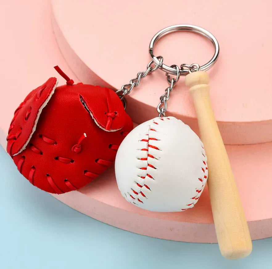 Baseball, glove and bat keychain on a tan table. 