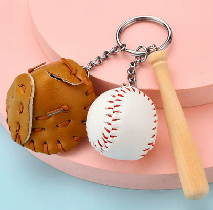 Baseball, glove and bat keychain on a tan table. 