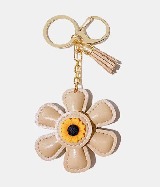 Handmade beige leather daisy keychain with yellow center and gold lobster clasp.