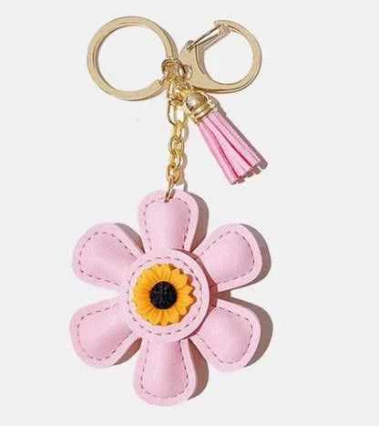 Handmade white leather daisy keychain with yellow center and gold clasp.