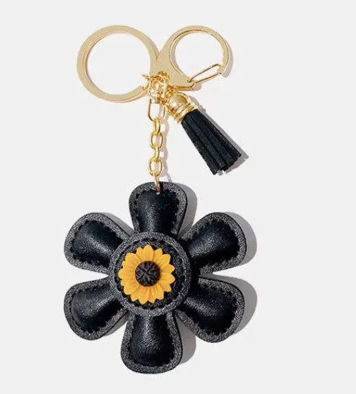 Handmade black leather daisy keychain with yellow center and gold clasp.